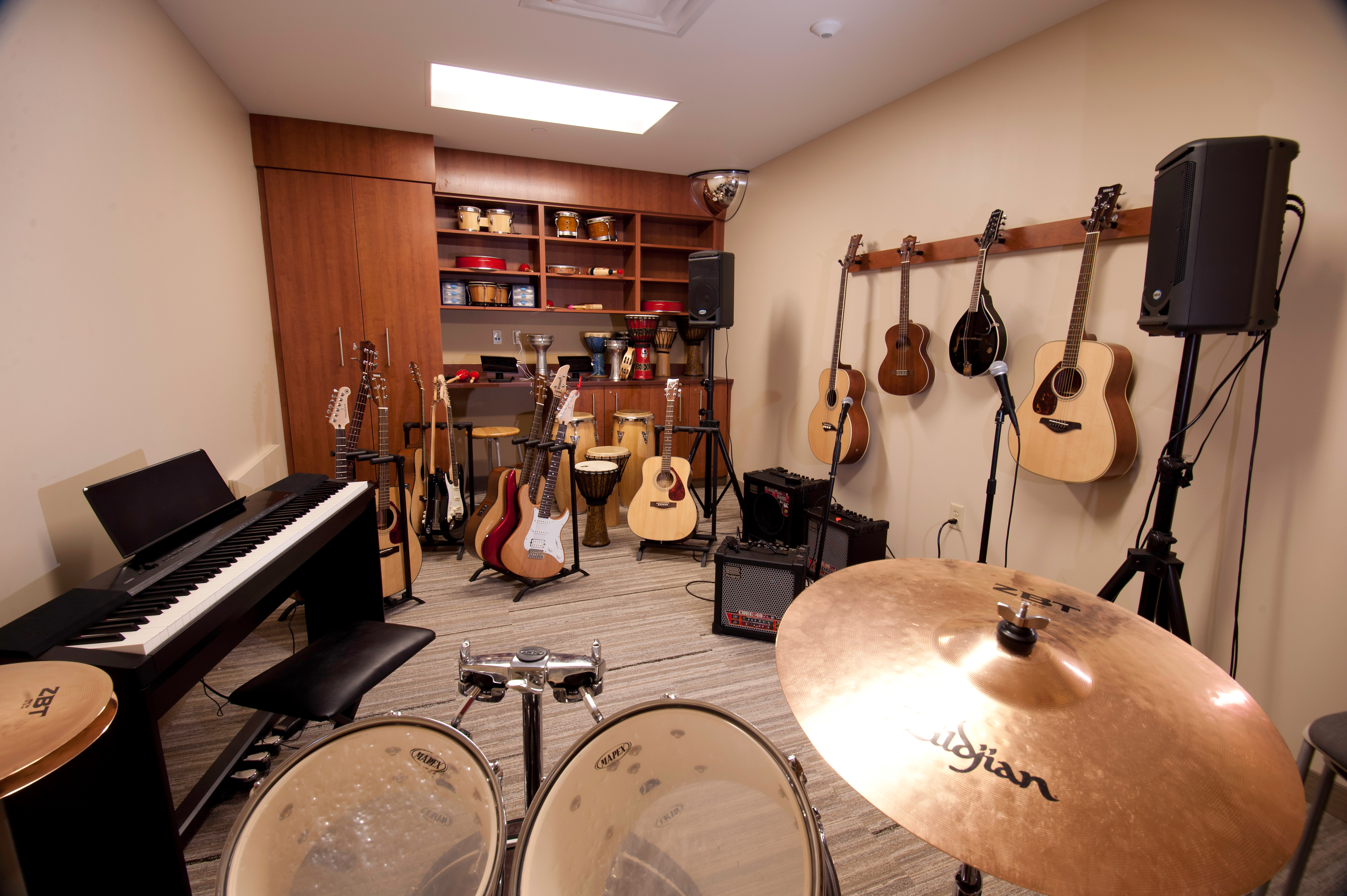 The Plymouth music room full of instruments like a piano, guitars, and a drum set