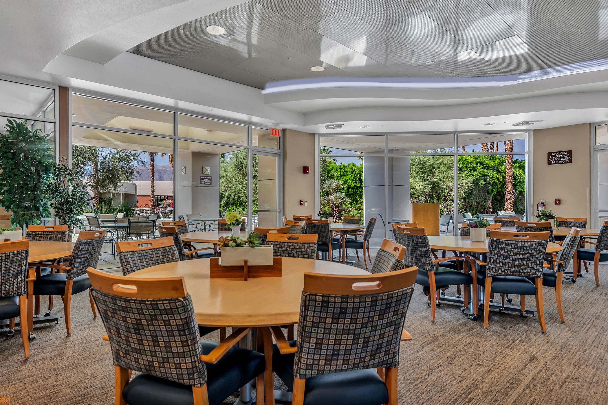 View of the dining room with multiple tables, chairs and large windows