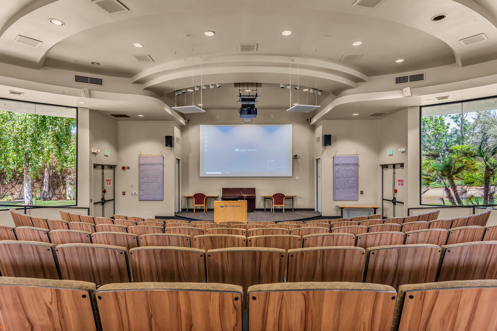 Inside a large auditorium with chairs and large windows