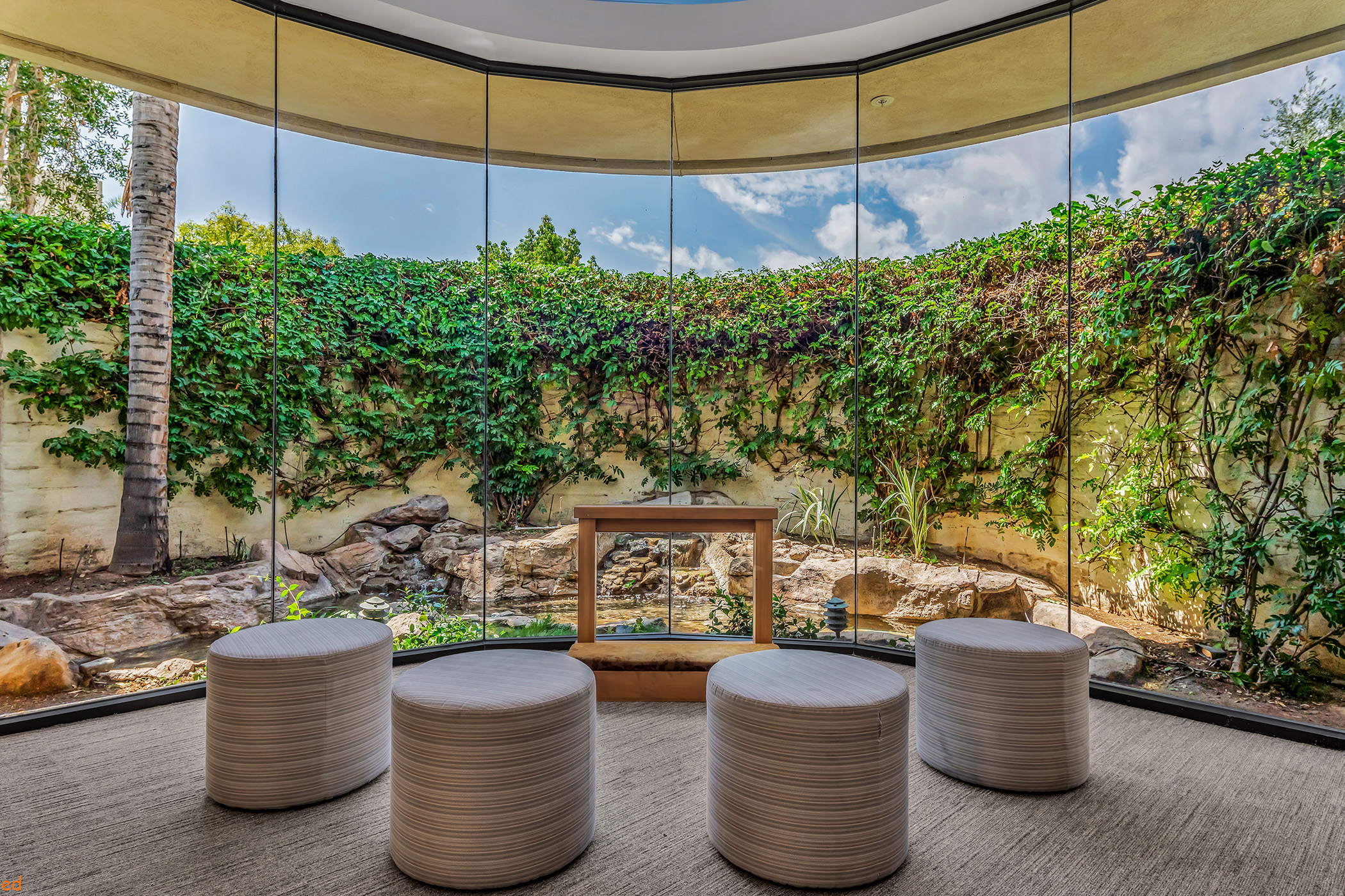 A bright meditation room with large windows and comfortable stools