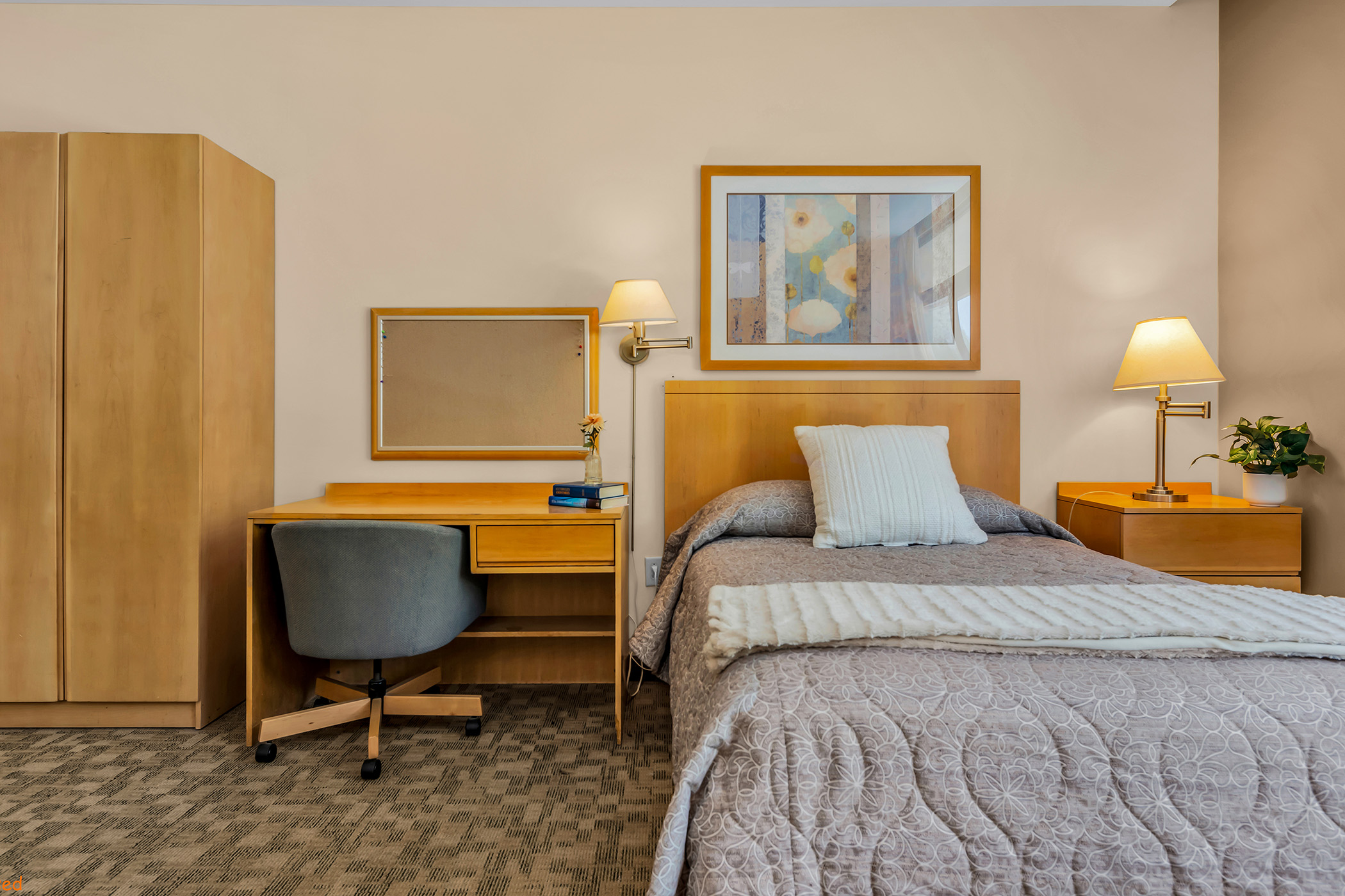 Inside a bedroom with a comfortable bed, a dresser and a small desk