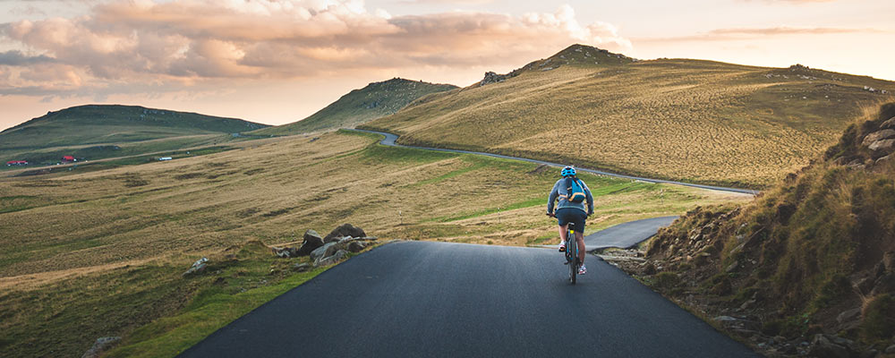 Bicyclist riding along a roadway through the hilly countryside