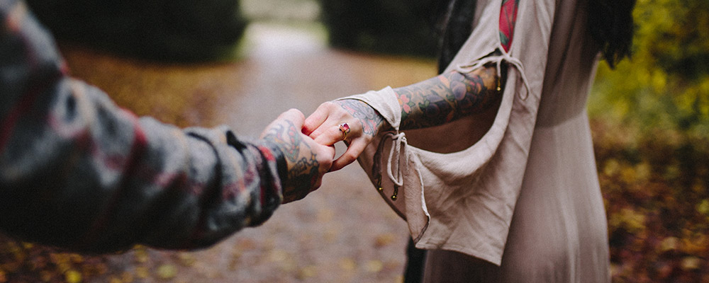 Couple with tattoos on arms, holding hands